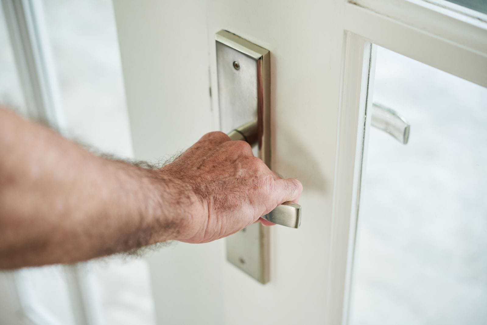 Hand an einer Türklinke beim Öffnen einer Haustür