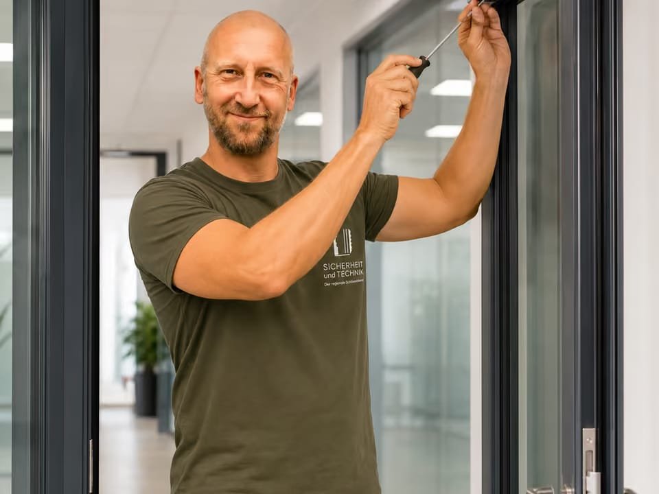 Thomas Heuberger montiert einen Türschließer an einer Glastür